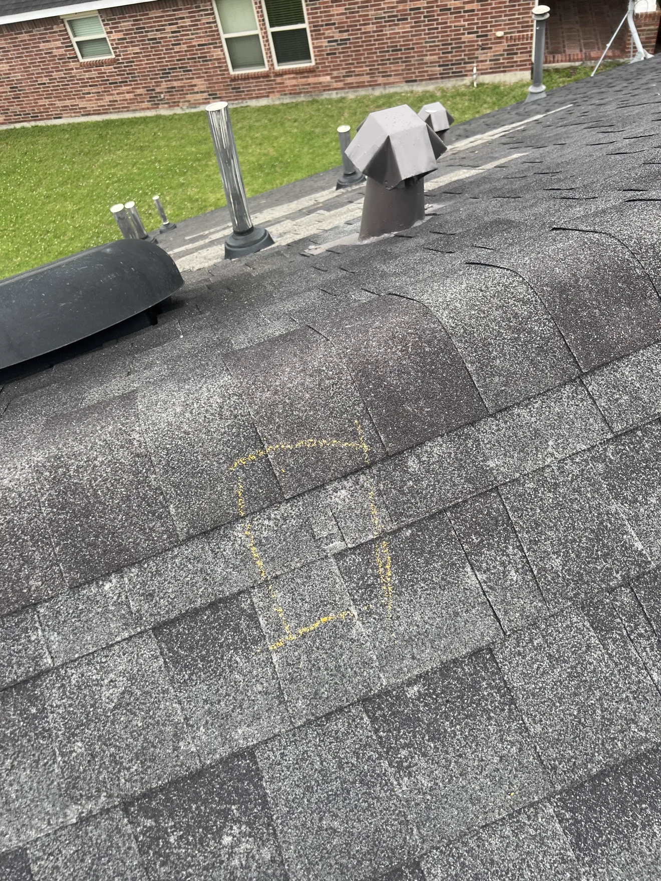 Storm damage marked with chalk on asphalt shingles for documentation